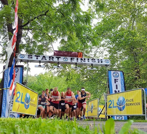 Runners starting a race under a START/FINISH archway, with yellow banners on either side.