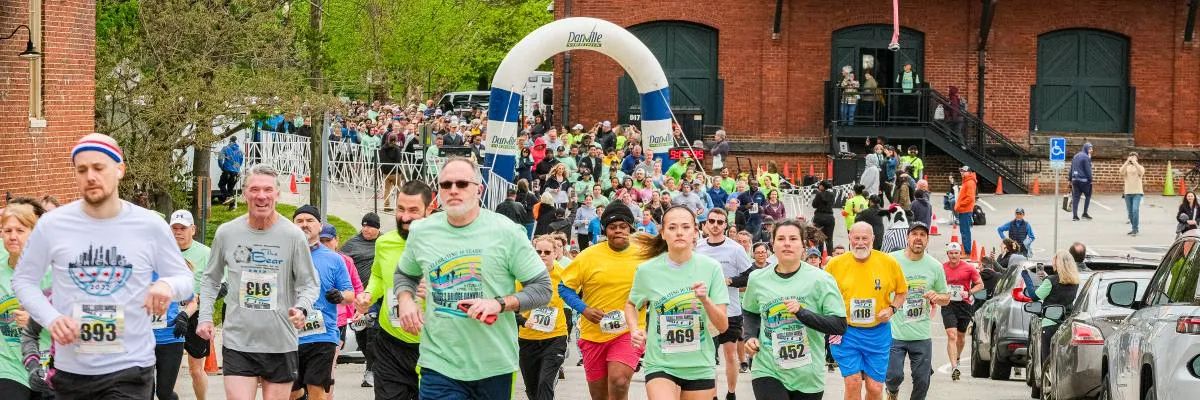 Runners crossing the start line under an inflatable arch at the Bridge2Bridge race.