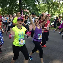 Runners smiling and waving at the camera during a race.