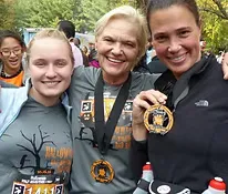 Three smiling women wearing race medals after completing the Superhero Half Marathon and Relay.