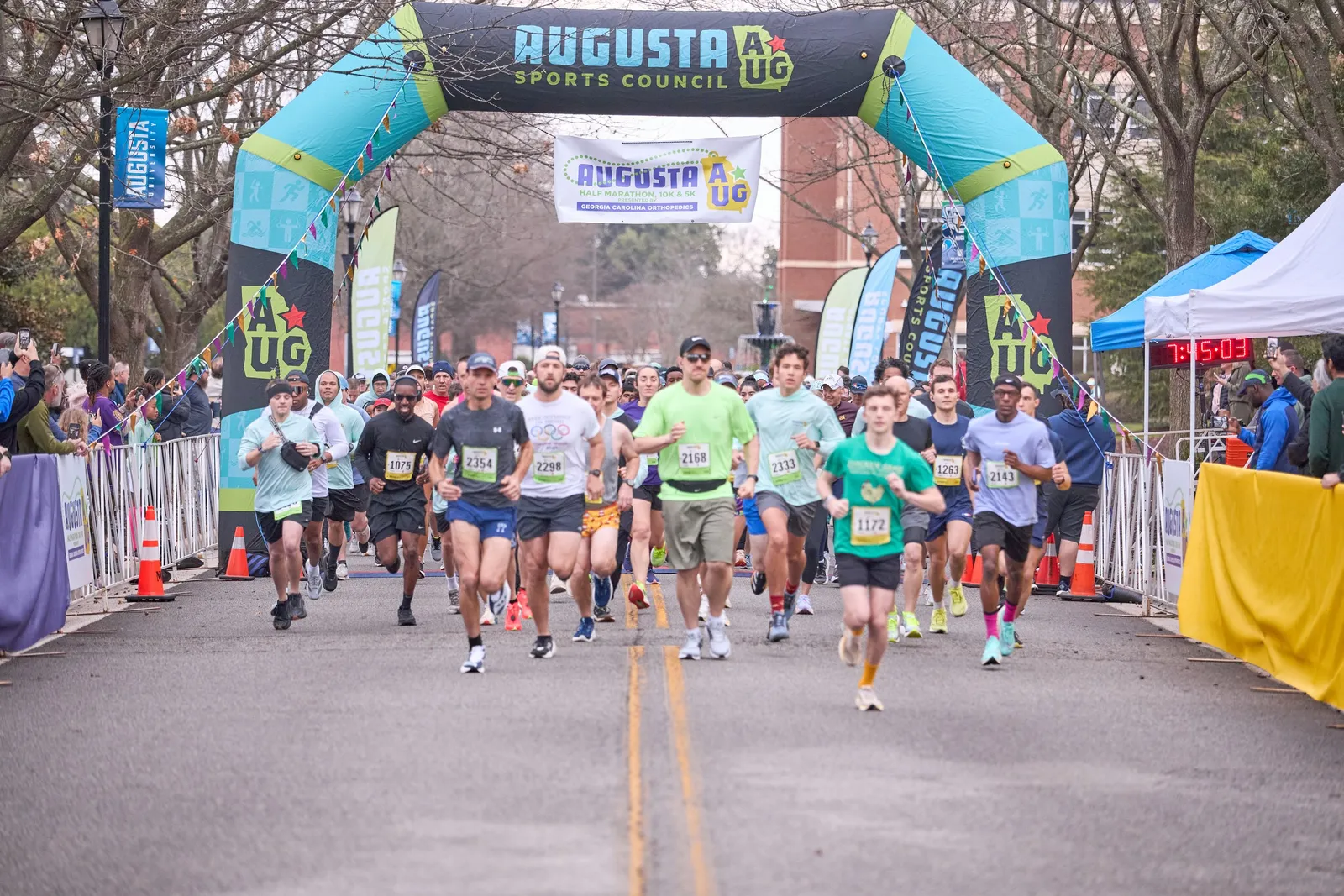 Runners starting the Augusta Half Marathon, 10K, & 5K under an inflatable arch.