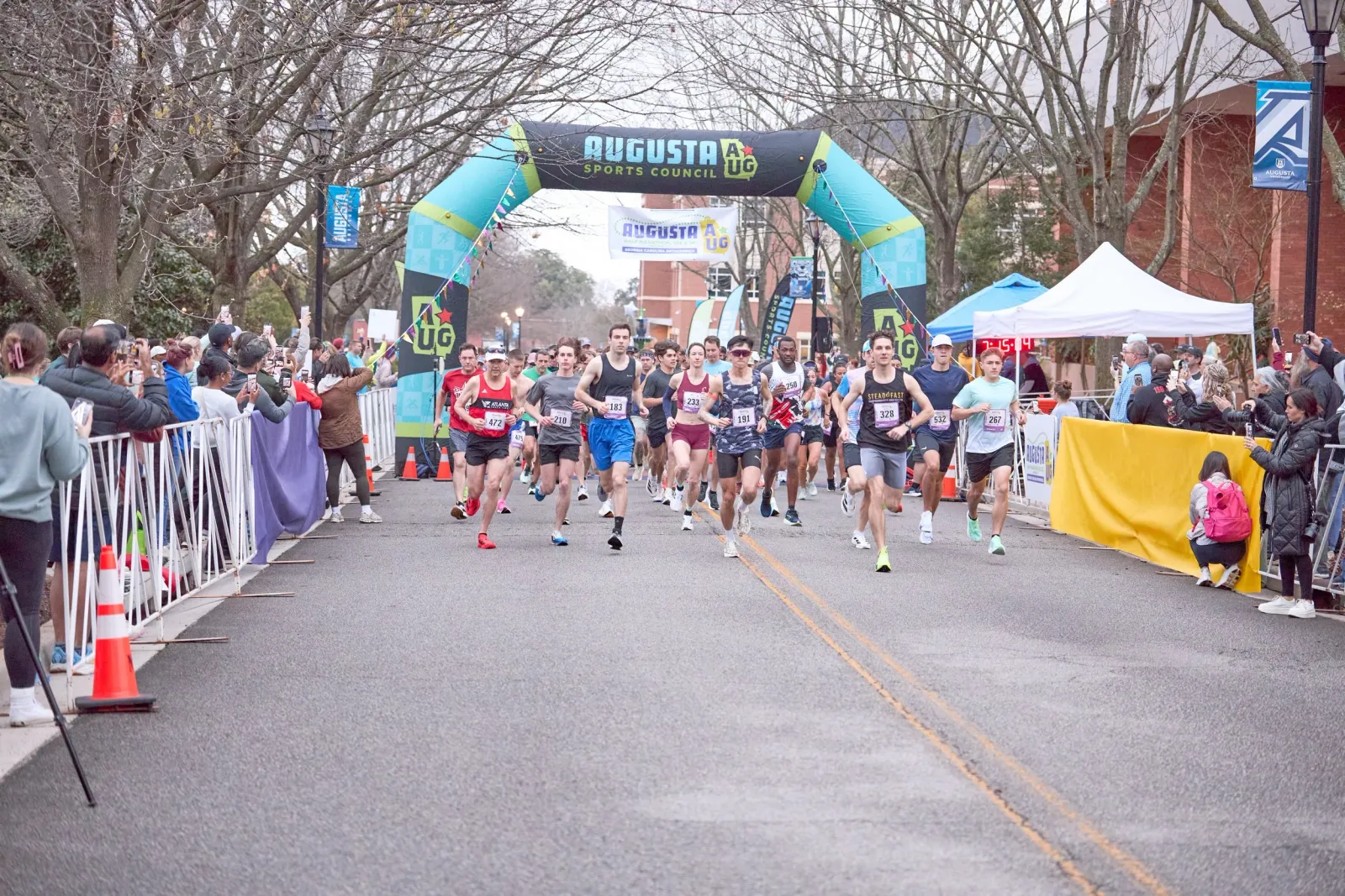 Runners starting a race under an inflatable archway, with spectators watching from the side.