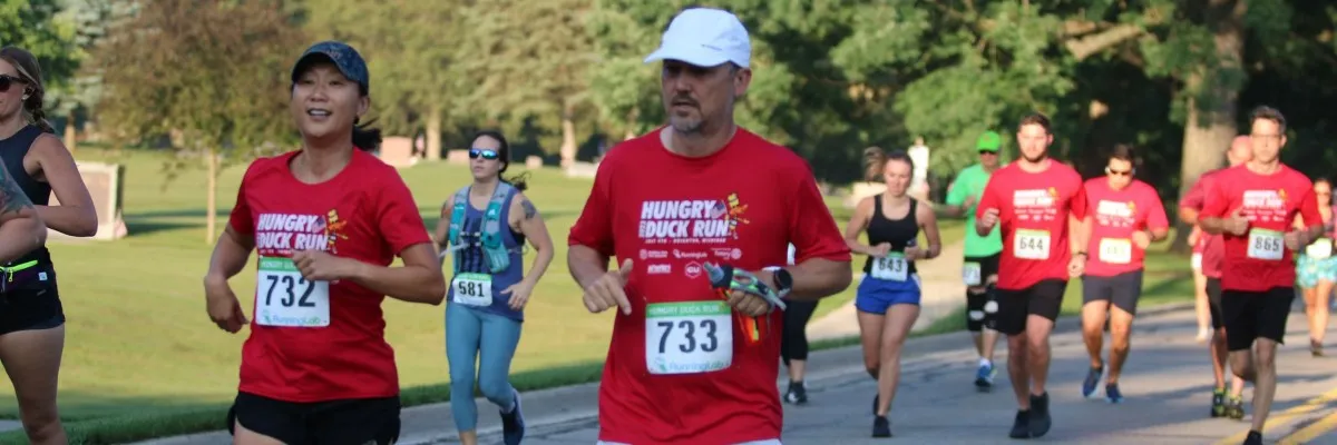 Runners in red shirts with bib numbers participate in the Hungry Duck Run.