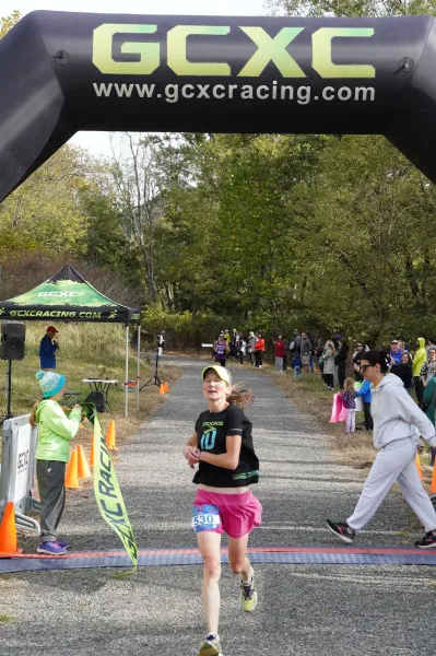 A female runner with a bib number 530 crosses the finish line at the Buffalo Creek Half Marathon, with spectators and an inflatable arch in the background.