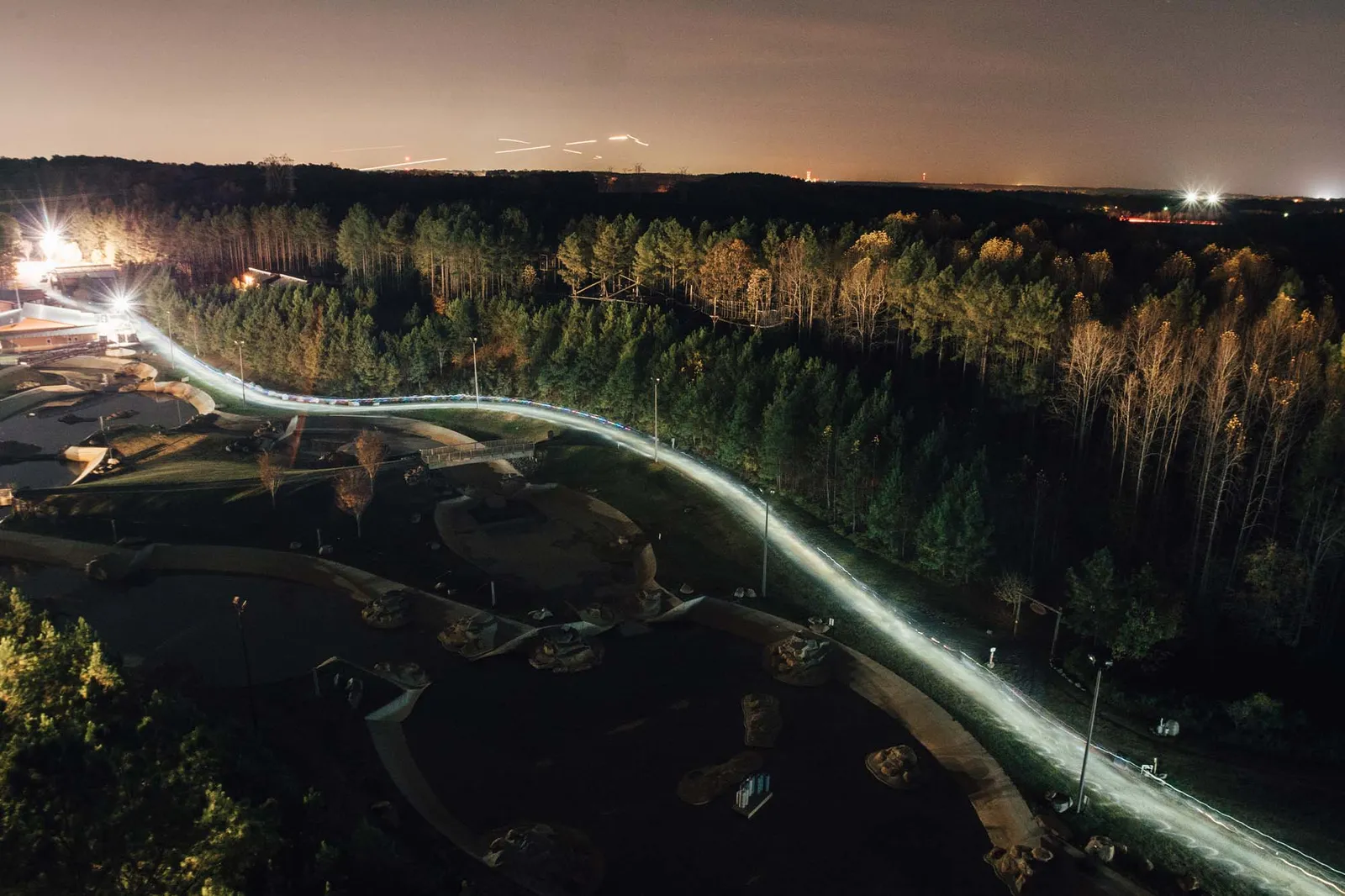 Long exposure night photo of a race course with light trails from runners winding through trees and parkland.