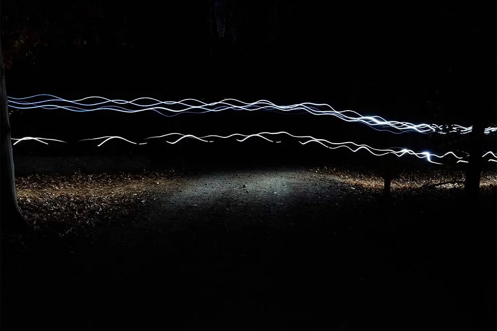 Light trails on a dark night trail, suggesting a night race.
