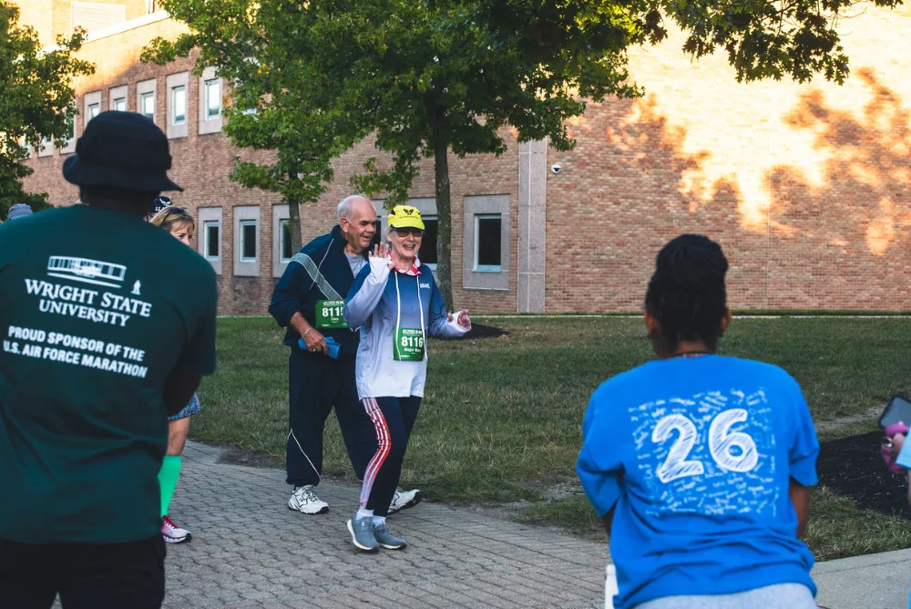 Runners at the start of a race, with one woman waving and smiling.