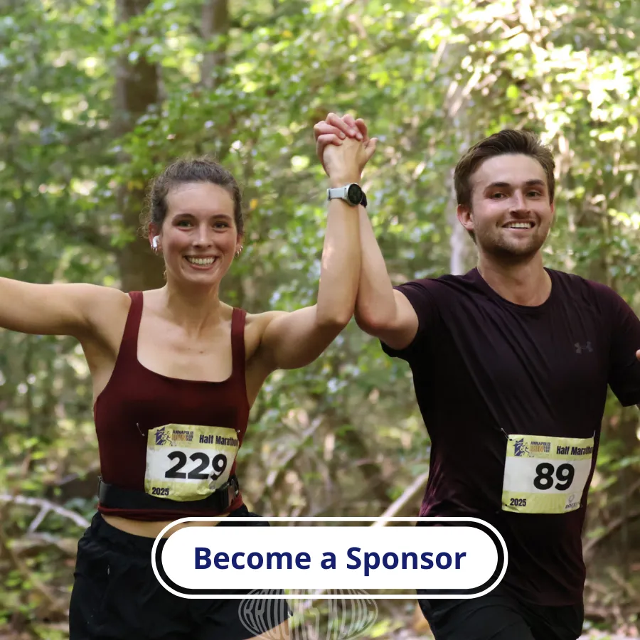 A male and female runner, holding hands up in celebration, with bib numbers visible, running on a wooded path.