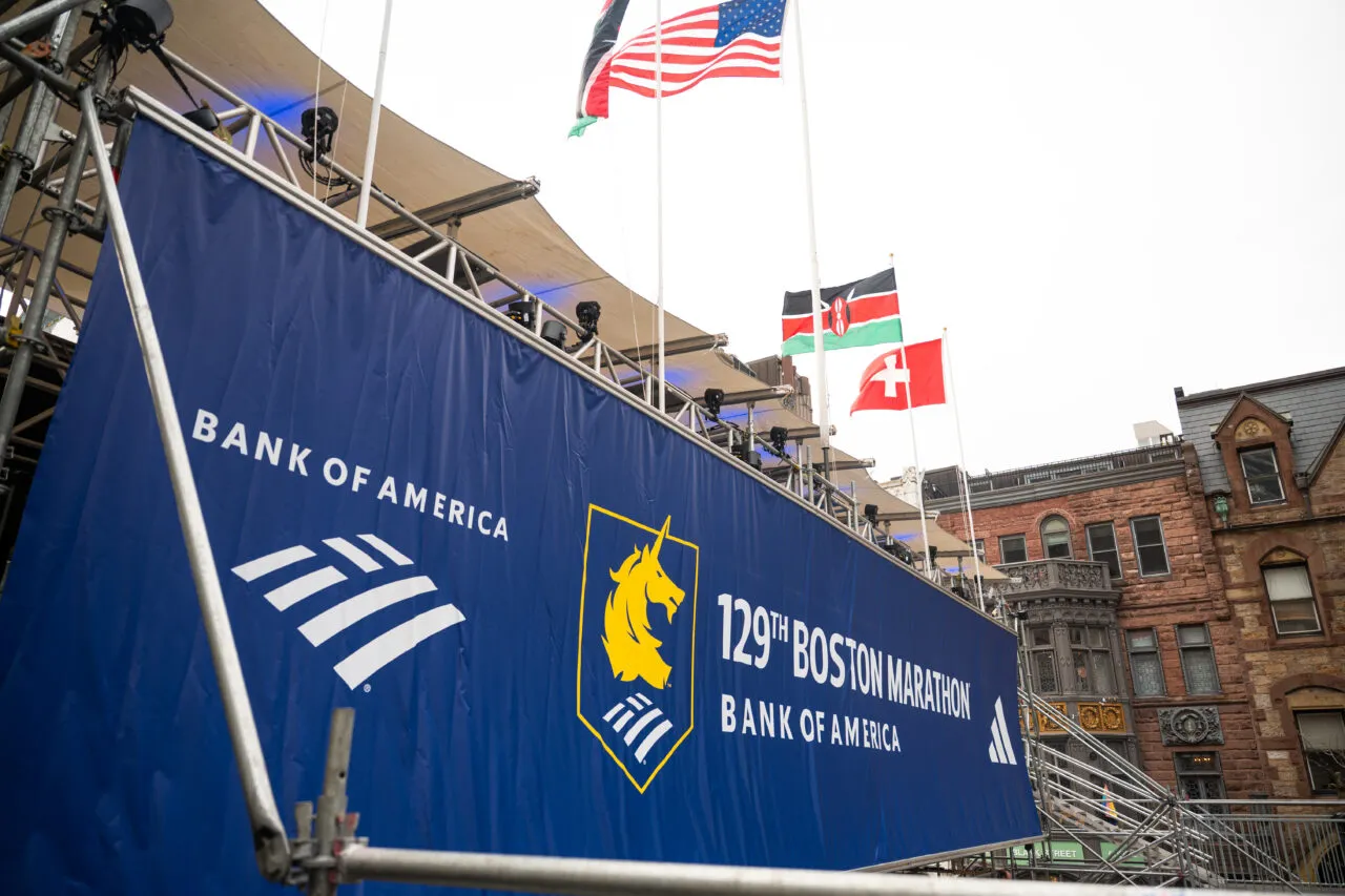 Banner for the 129th Boston Marathon with Bank of America branding and flags.