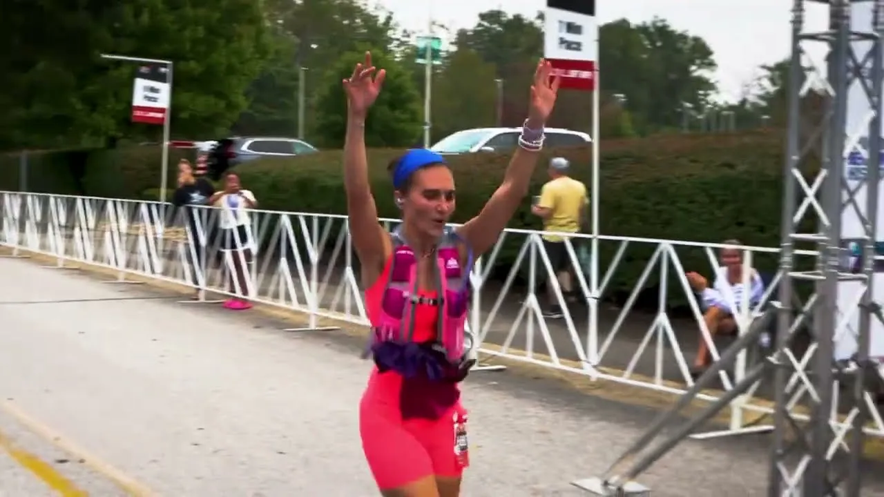 A female runner with her arms raised in celebration as she crosses the finish line of a race.