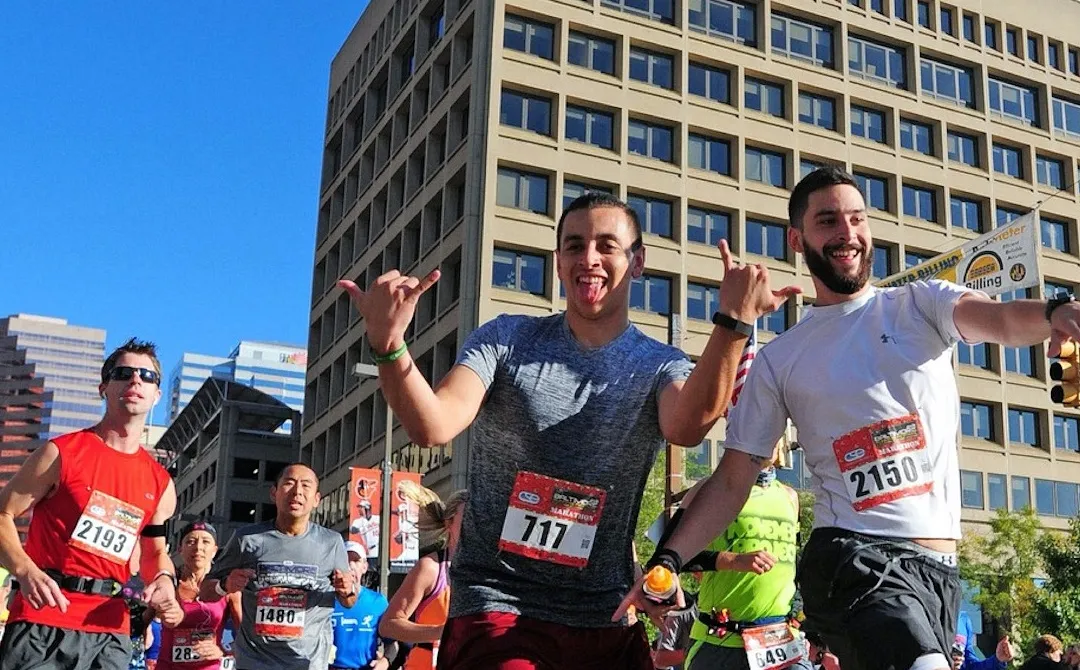 Runners celebrating during a city marathon, with buildings in the background.