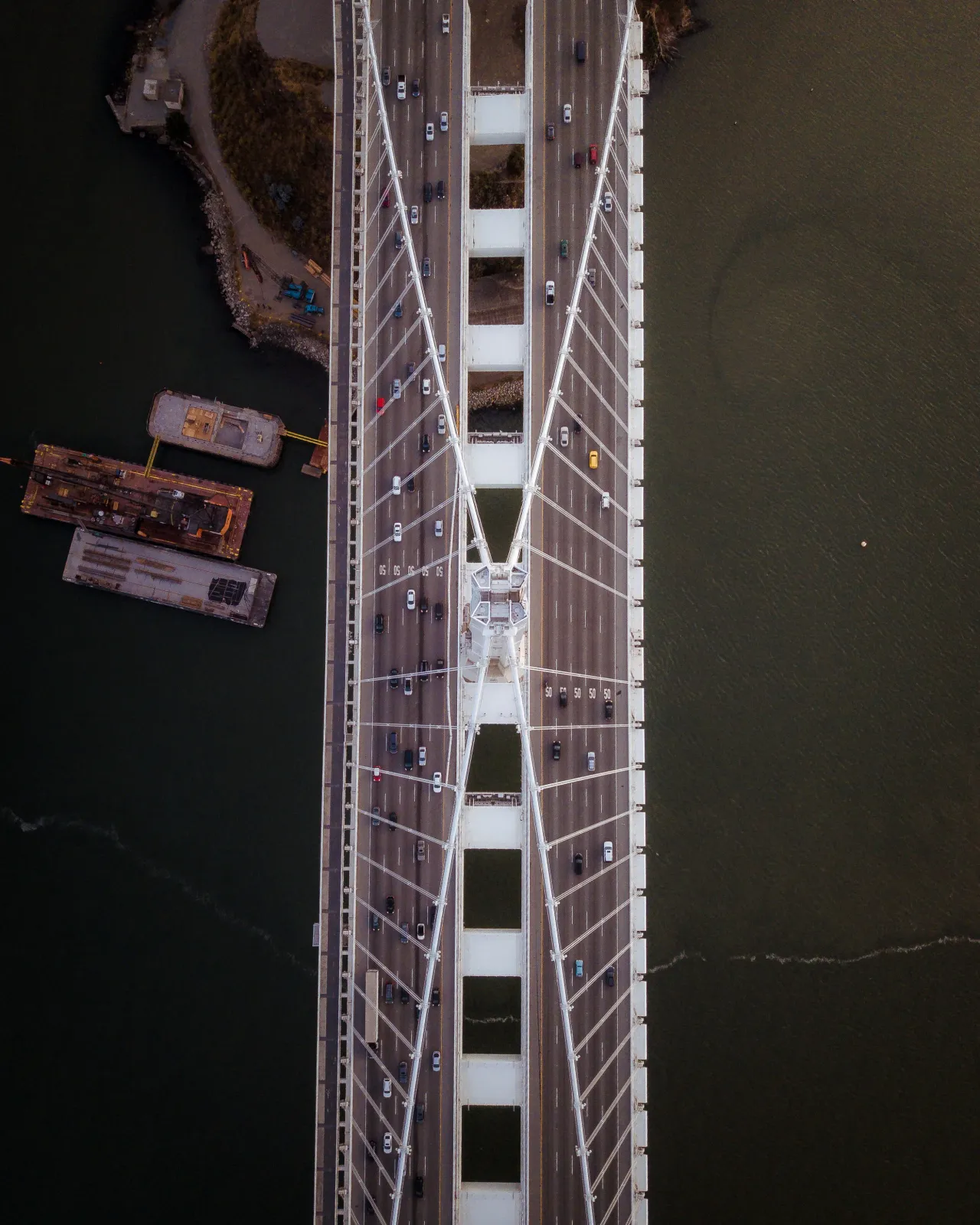 Aerial view of the Bay Bridge with cars on the road and water below.
