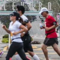 Runners on a road with a blurred sign in the background.