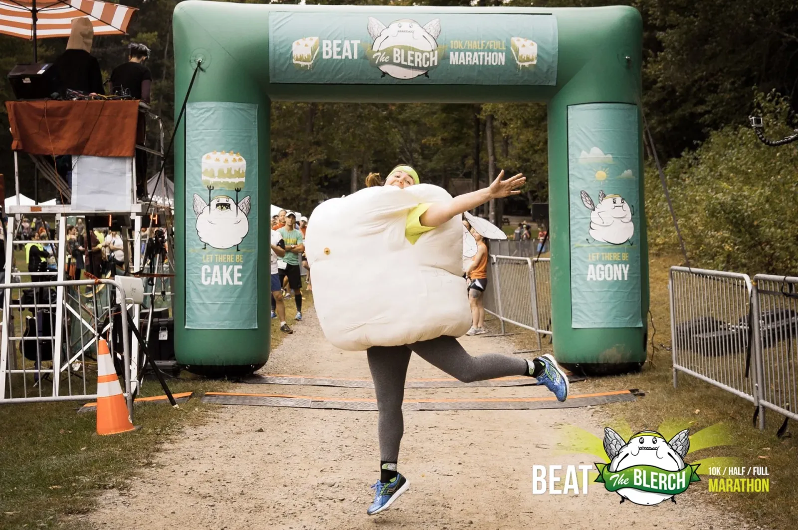 A runner in a large, white inflatable costume jumps with joy at the start/finish line of the Beat the Blerch Marathon.