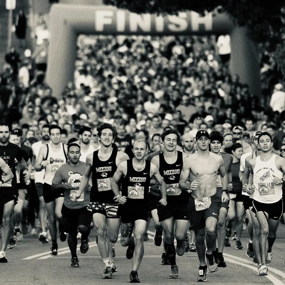 A large group of runners approaching the finish line at a race, with the word 'FINISH' visible on an archway in the background.