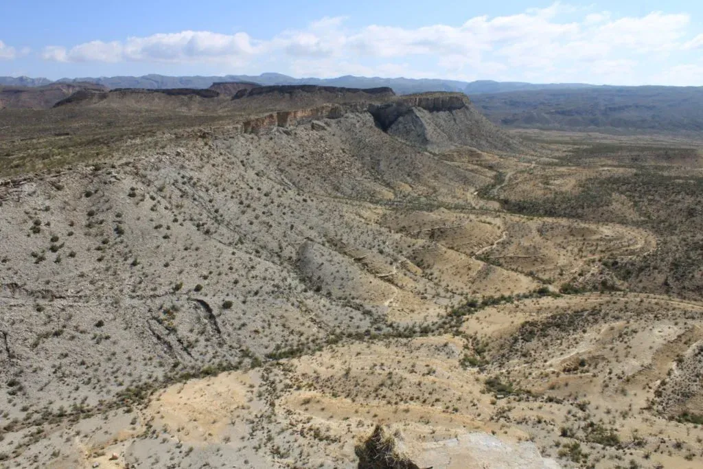 Scenic view of rugged, arid hills and valleys with a winding dirt path visible, suggesting a trail race course.