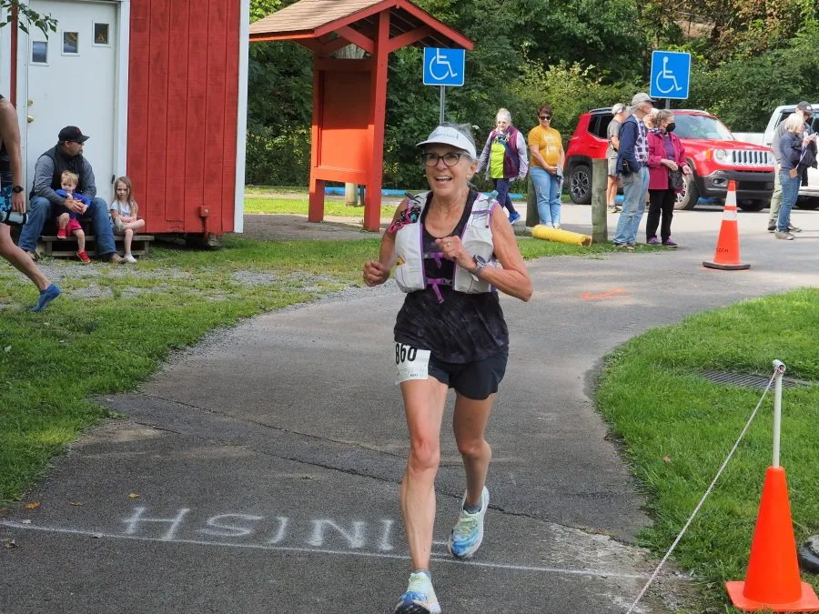 A female runner smiles as she crosses the finish line.