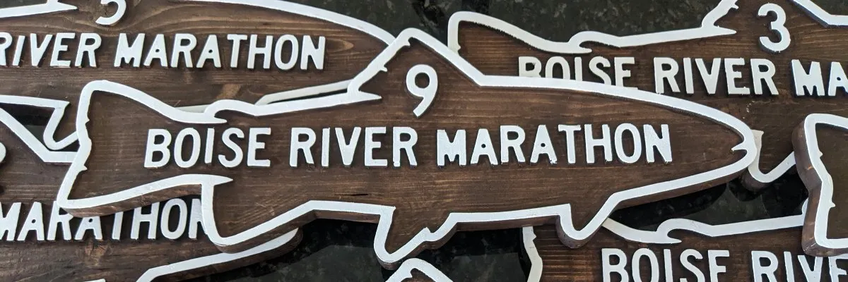 Close-up of wooden Boise River Marathon medals shaped like fish.