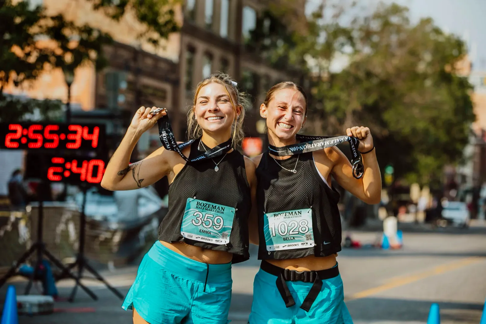 Two smiling female runners proudly display their medals after completing the Bozeman Half Marathon.