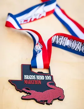 Brazos Bend 100 Marathon medal shaped like Texas with an alligator graphic.