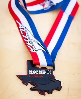 Brazos Bend 100 Half Marathon medal shaped like Texas with an alligator graphic.