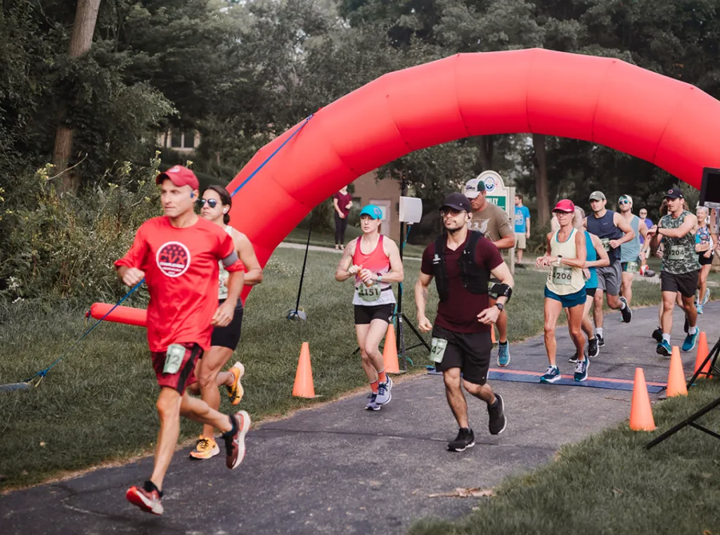 Runners crossing the start line under a large red inflatable arch at the Back Roads Bound Half Marathon.