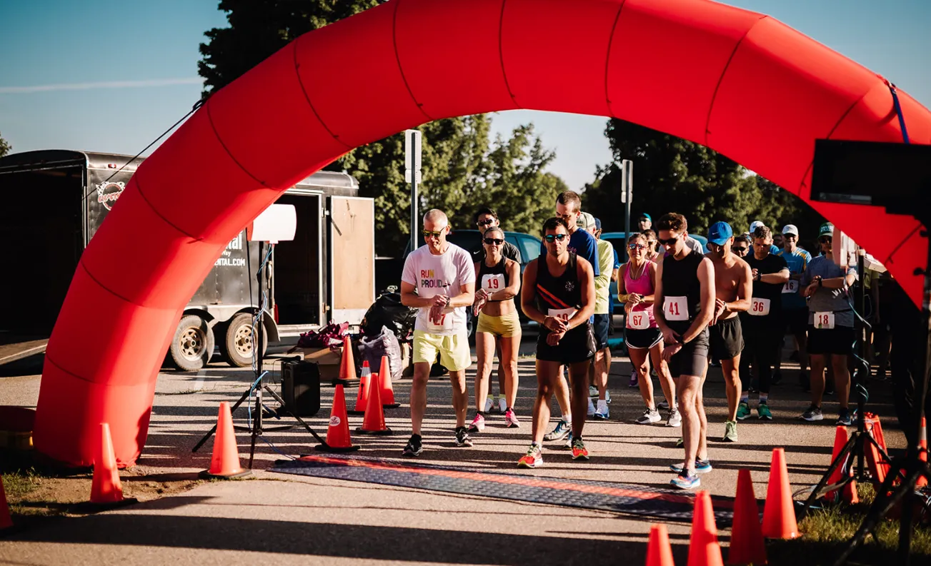 Runners lined up at the start line under a large red inflatable arch, waiting for the race to begin.