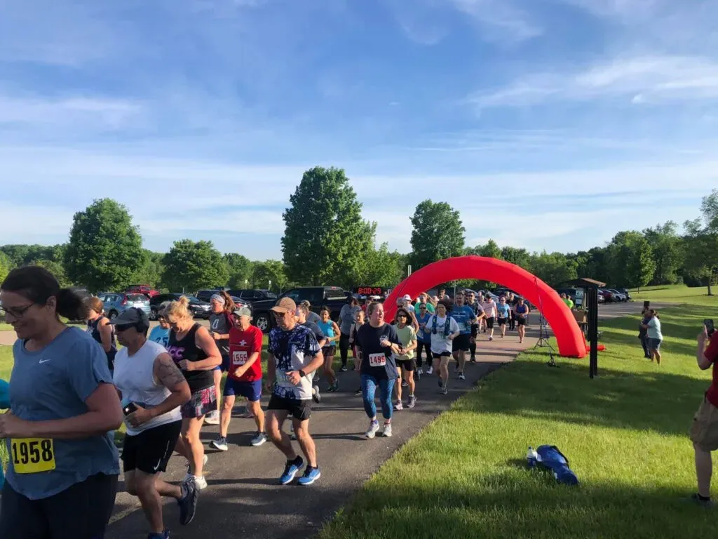 A group of runners are starting a race, passing under a red inflatable archway.