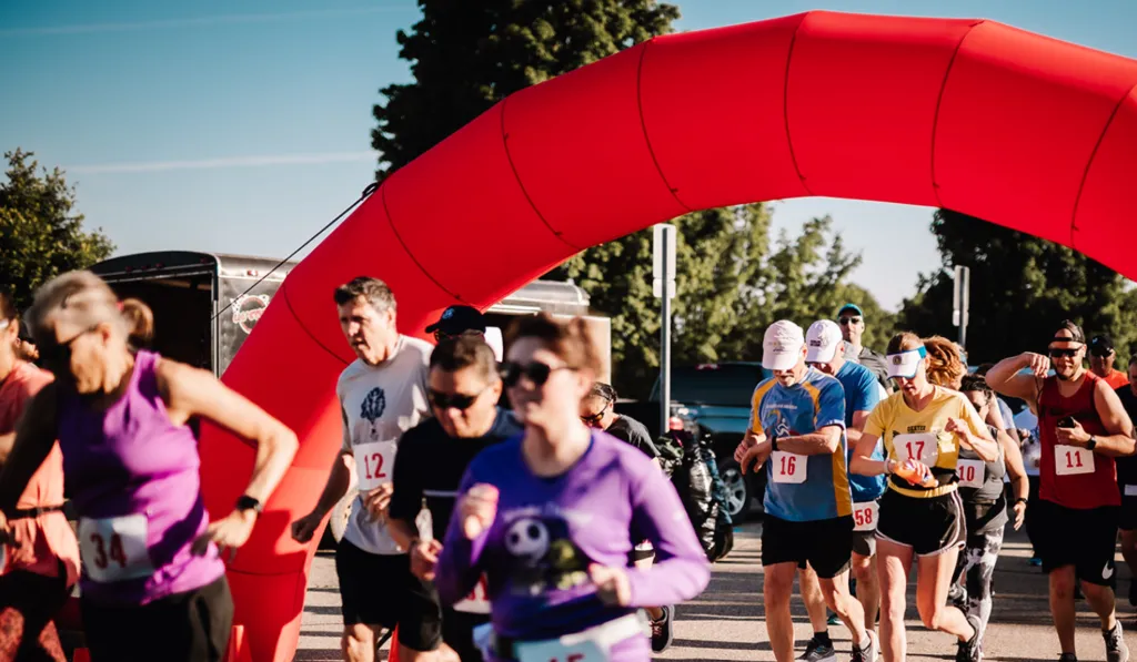 Runners crossing the start line under a red inflatable arch at the Back Roads Bound Half Marathon.