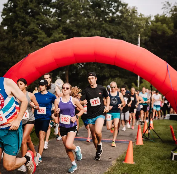 Runners crossing the start line under a red inflatable arch at the Back Roads Bound Half Marathon.