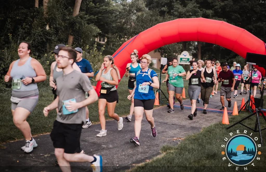 Runners crossing the start line under a red inflatable archway.