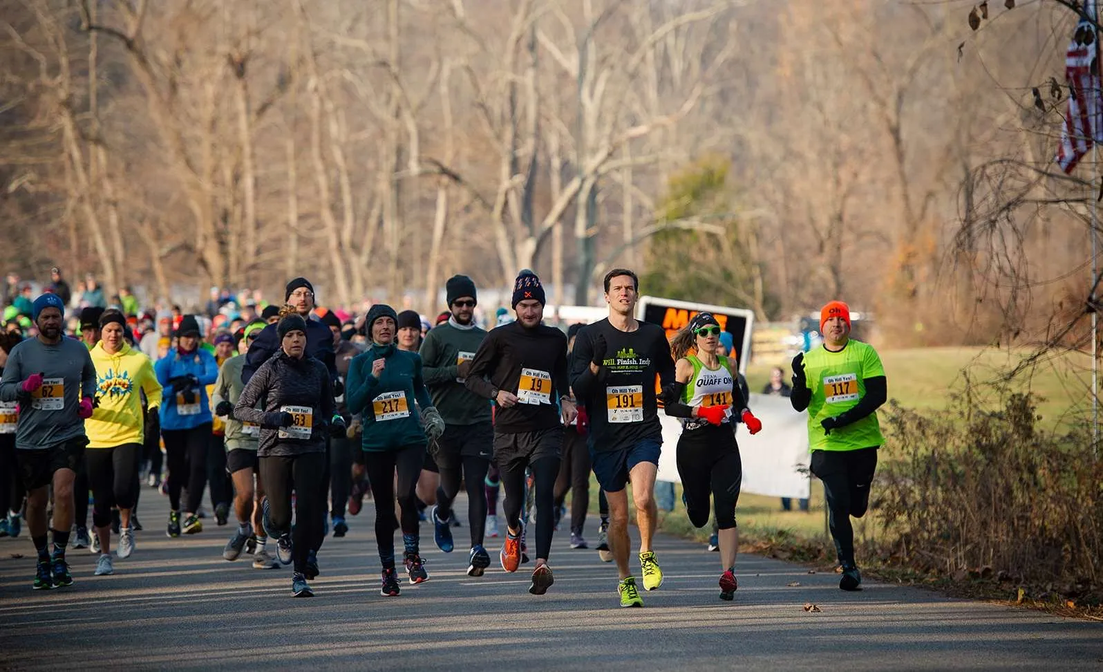 A group of runners in a race, with several in the foreground focused on running.