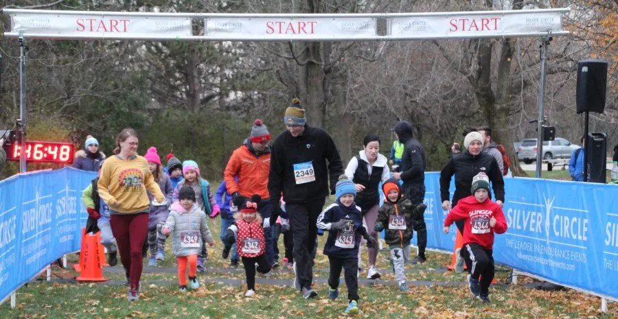 Runners, including many children, start a race under a 'START' banner.