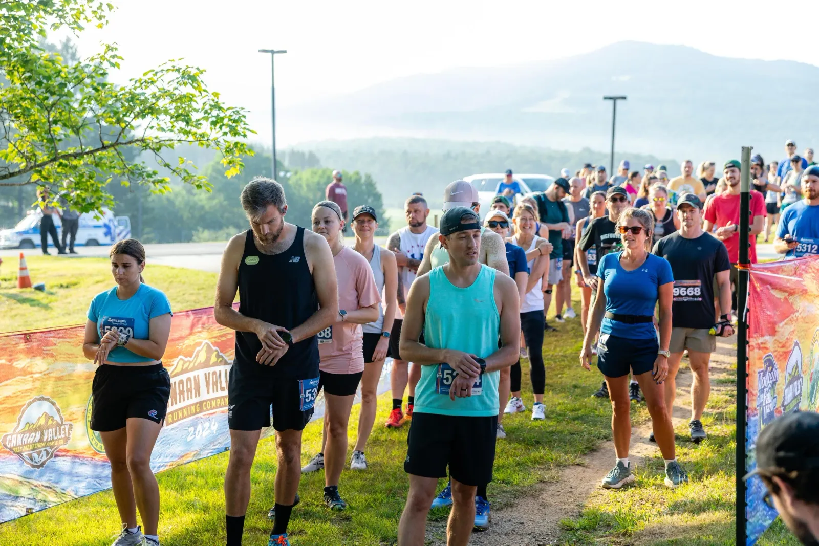 Runners in a line at the start of a race, with mountains in the background.