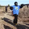 Runner in a gorilla costume with arms outstretched on a dirt trail.