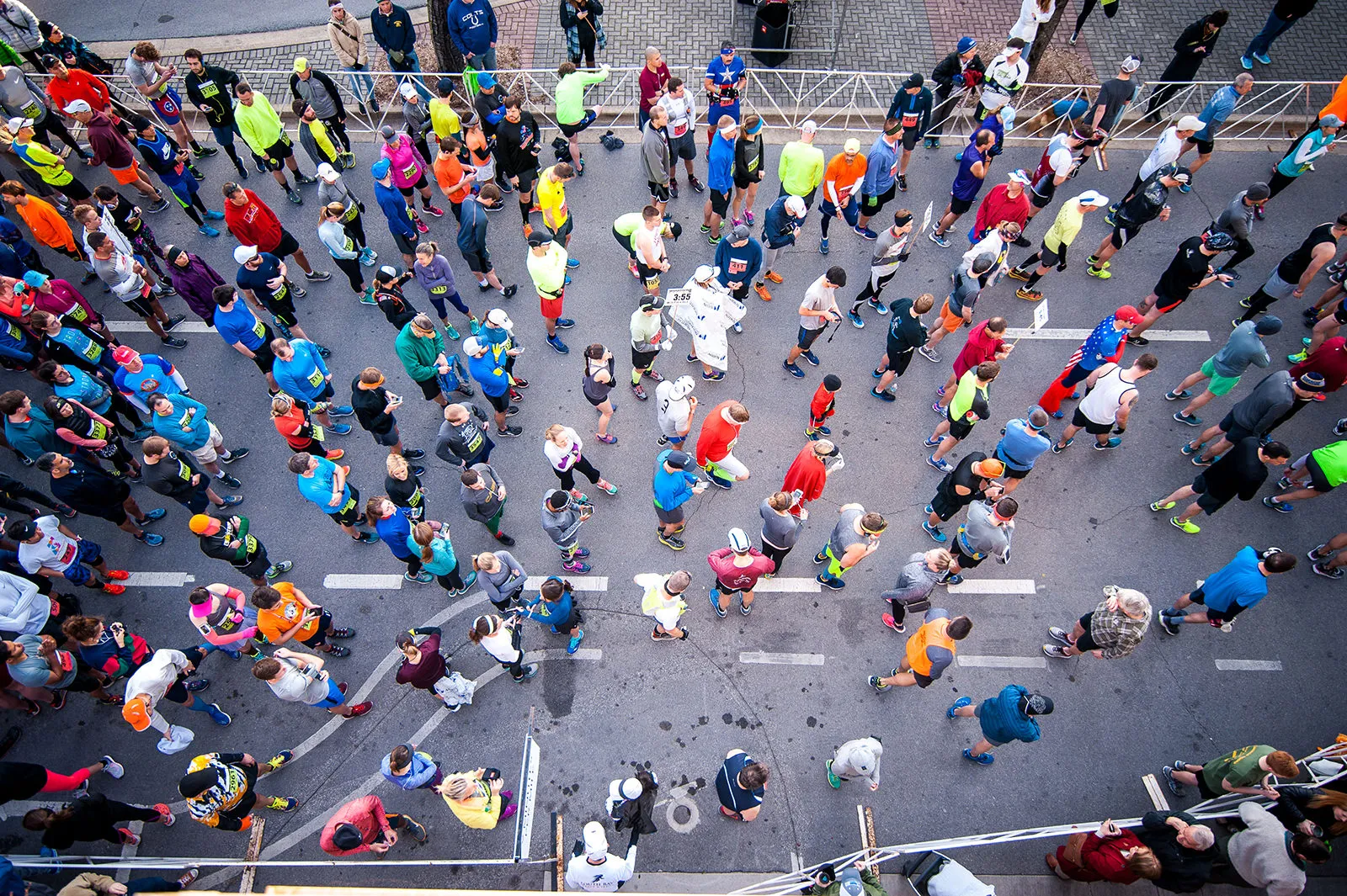 Overhead view of a large crowd of runners gathered at the start line of a road race.