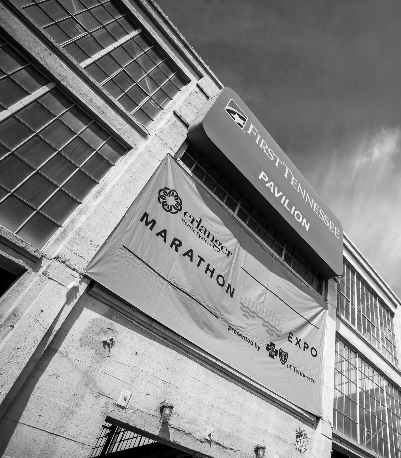 A black and white photo of a building with a large banner that reads "MARATHON" and a smaller banner above that says "FIRST TENNESSEE PAVILION".