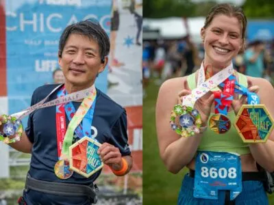 Two runners, a man and a woman, smiling and showing off their race medals from the Chicago Half Marathon.