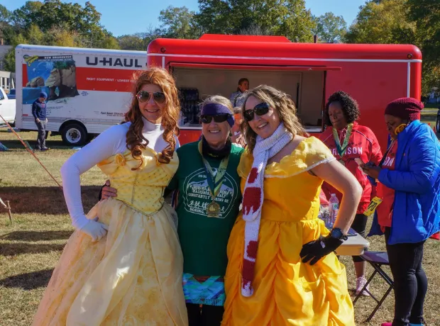 Three women in costumes and race medals pose for a photo at the finish line party.