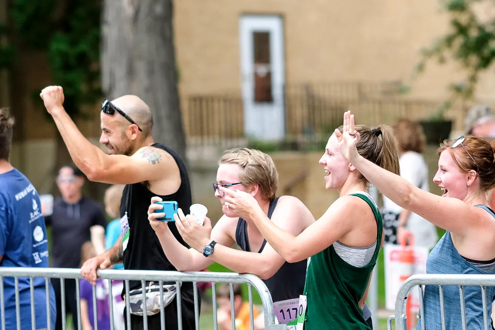 Spectators cheering and taking photos at a race.