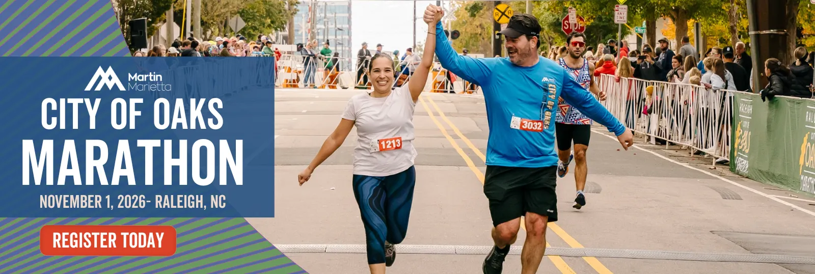 Two runners, a woman and a man, cross the finish line of the City of Oaks Marathon with their arms raised in celebration, while a crowd watches from behind barriers.