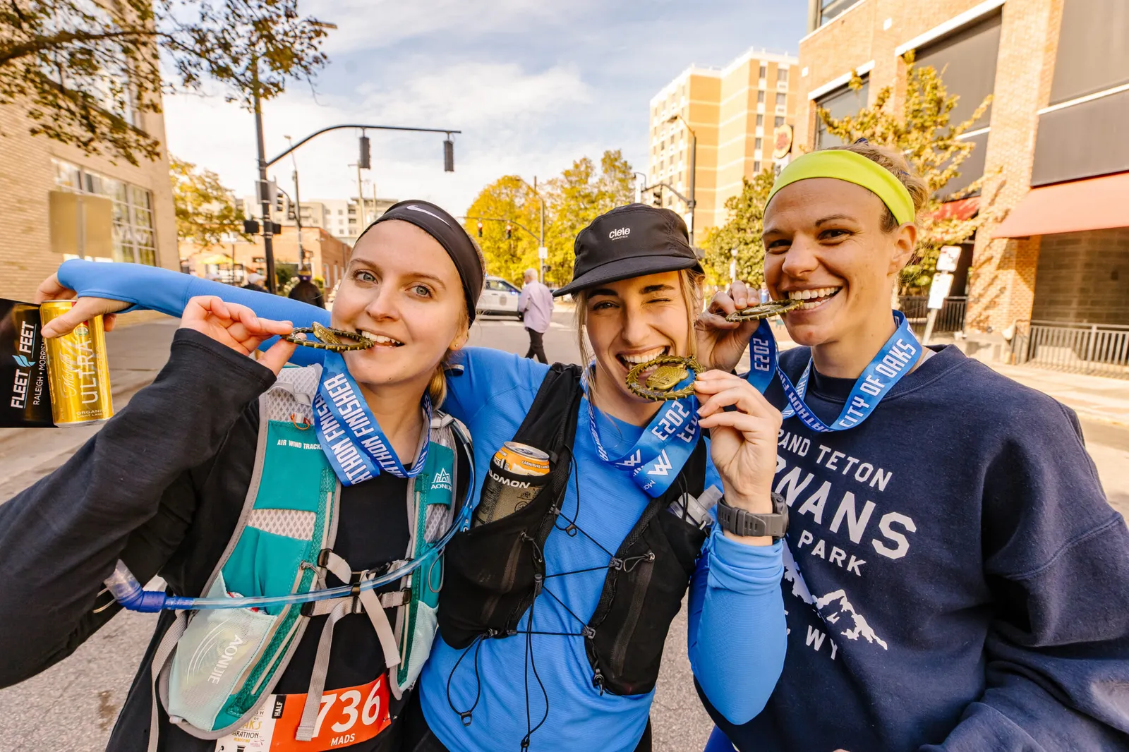 Three smiling runners proudly display their race medals after completing the City of Oaks Marathon.