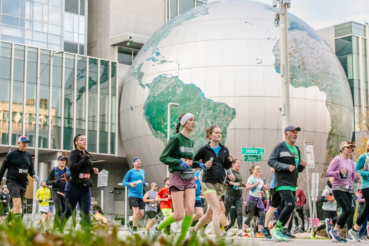 Runners participating in the City of Oaks Marathon pass by a large globe structure.