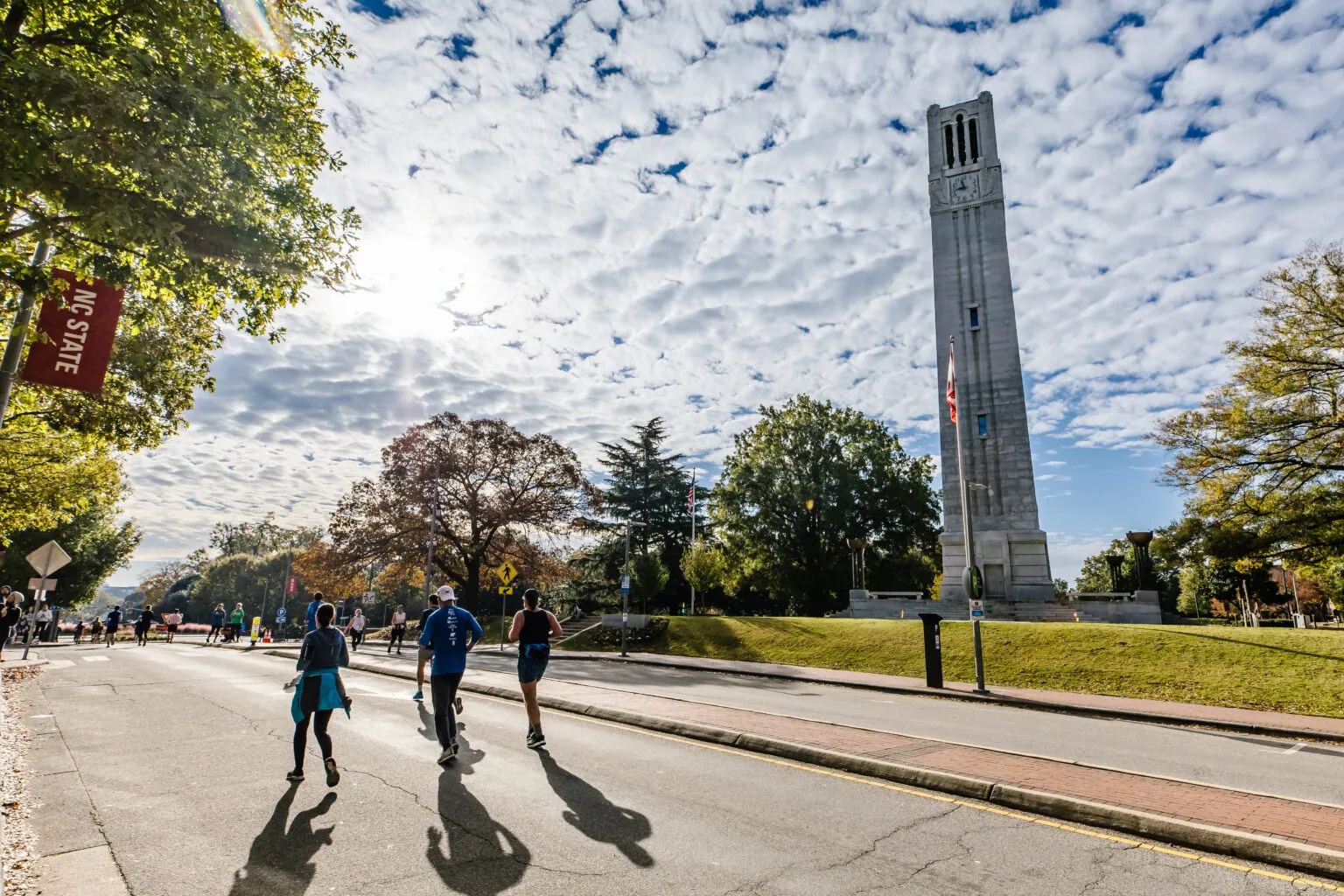 Runners on a road with a tall clock tower in the background.