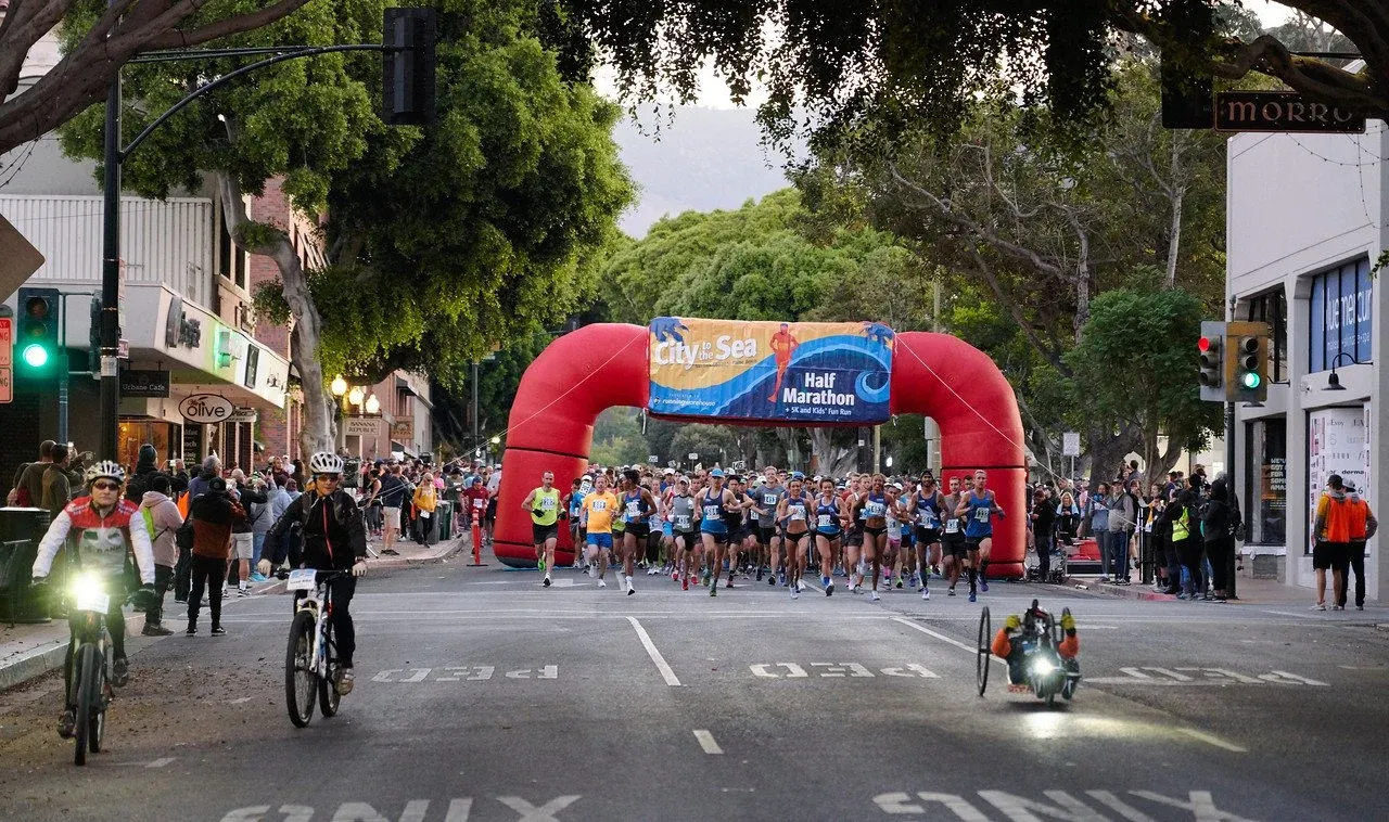 Runners starting the City to the Sea Half Marathon under a large inflatable arch.