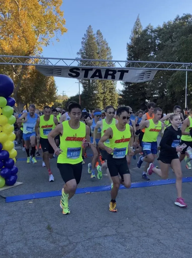 Runners in neon yellow shirts starting a race, with a 'START' banner overhead.