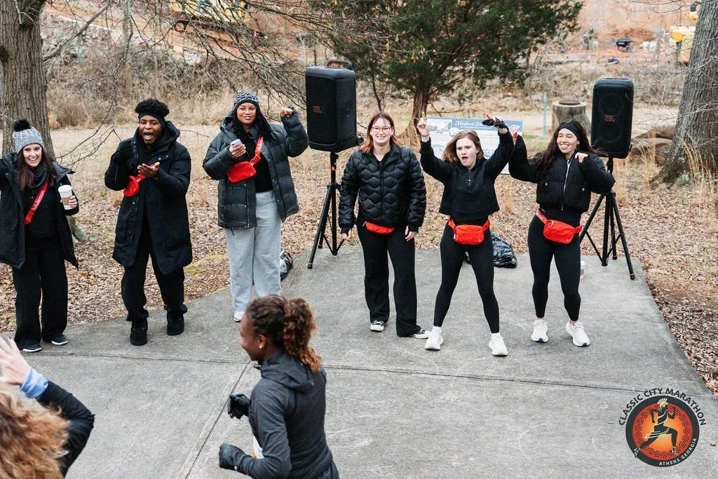 A group of people cheering and dancing at an outdoor event, with speakers set up.