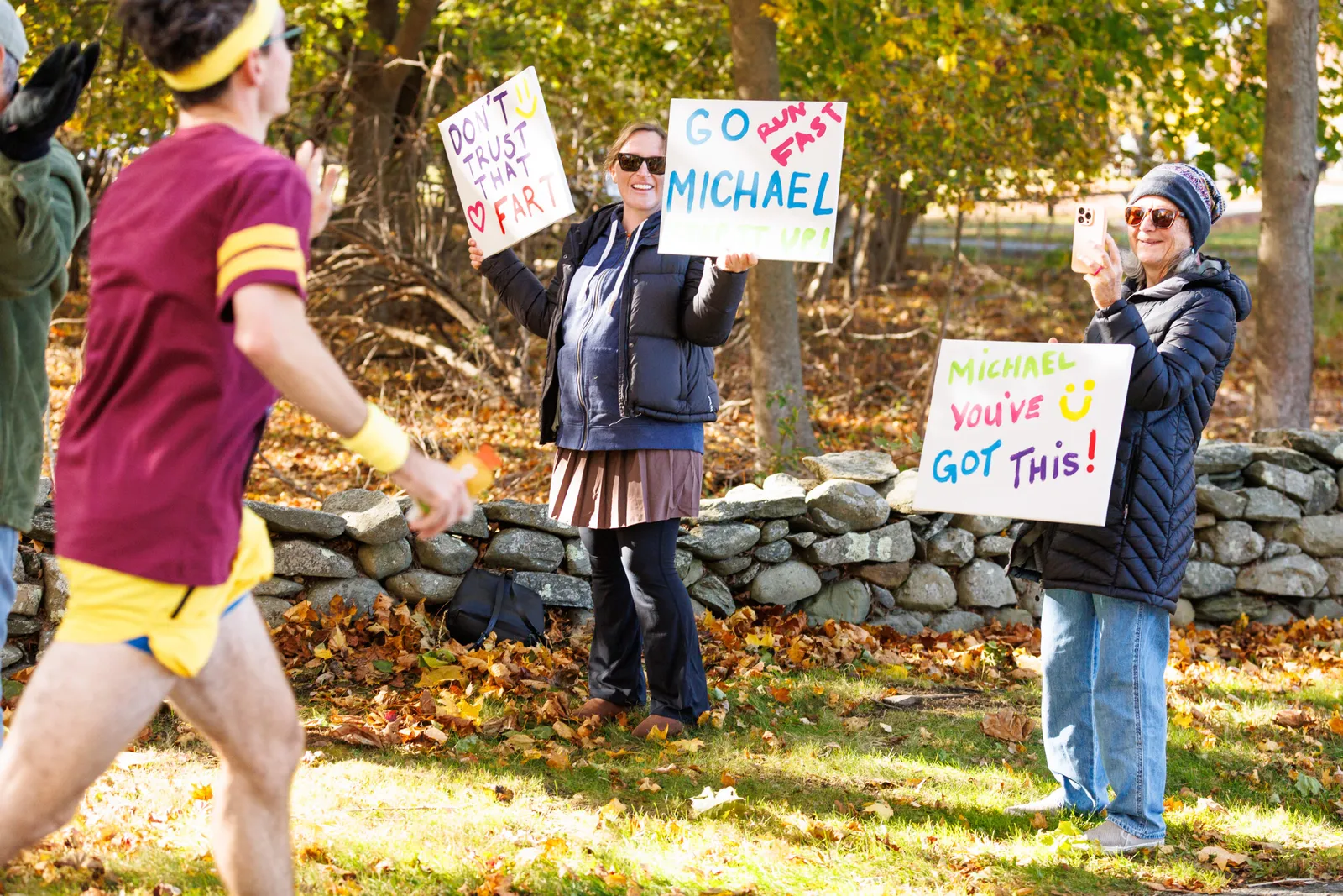 Spectators holding signs and cheering for a runner during a race.