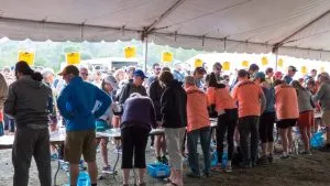 A crowd of runners and spectators gathered under a tent at the start line of the Covered Bridges Half Marathon.