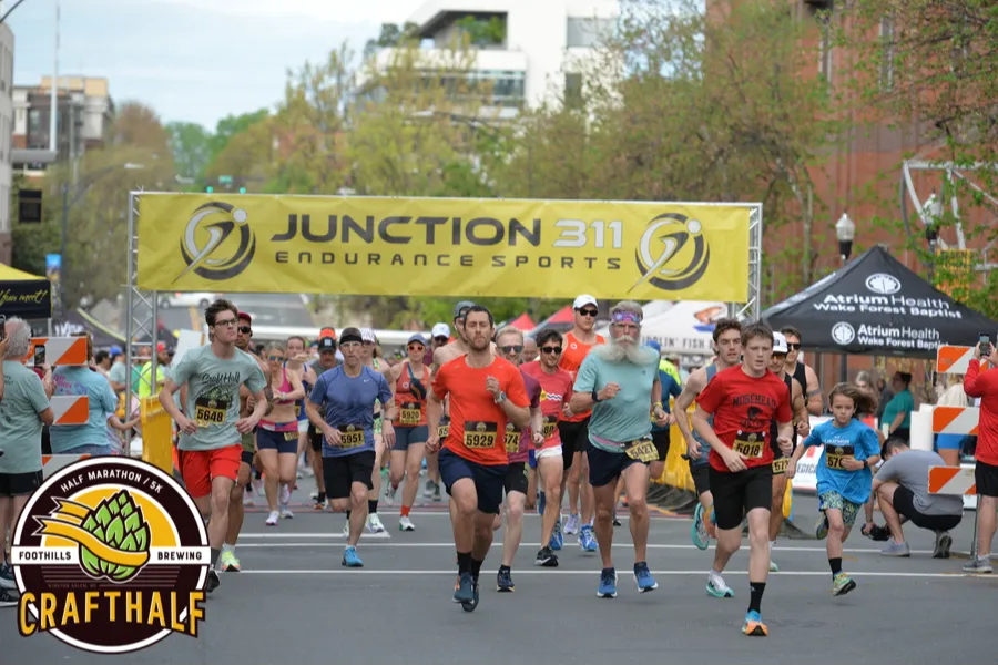 Runners starting the Crafthalf Half Marathon / 5K, with a Junction 311 Endurance Sports banner overhead.